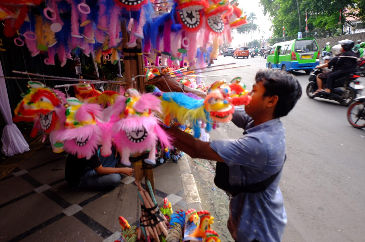 Seorang pedagang menjajakan boneka tangan Barongsai di sepanjang Jalan Surya Kencana, Bogor, menjelang perayaan Cap Go Meh 2025. Mainan ini diminati sebagai simbol keberuntungan dan kemeriahan Imlek.